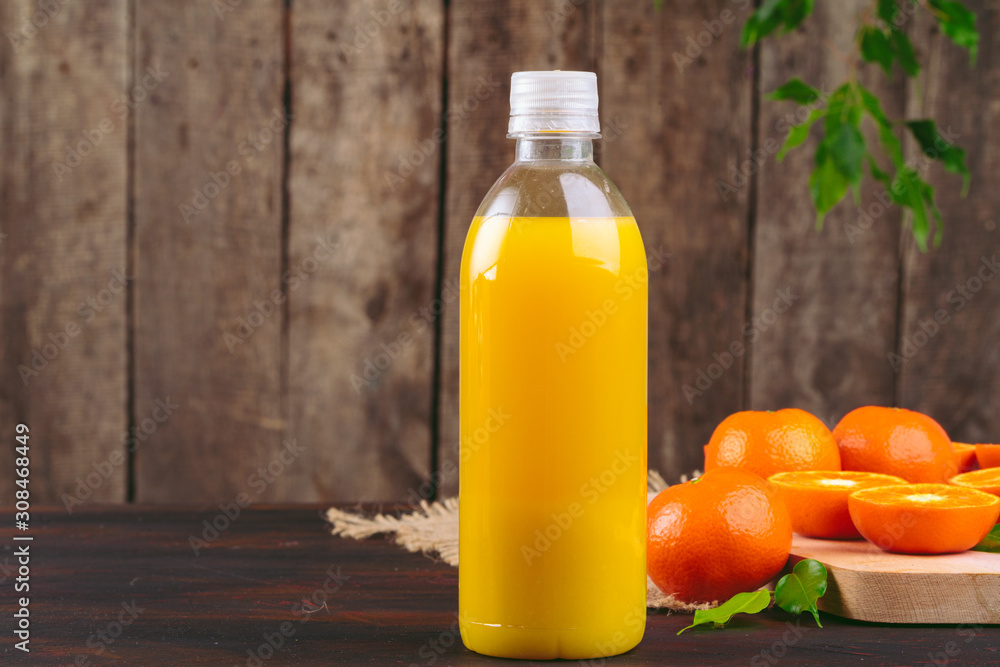 Bottle of orange juice with oranges on wooden table Bottle of orange juice with oranges on wooden table
