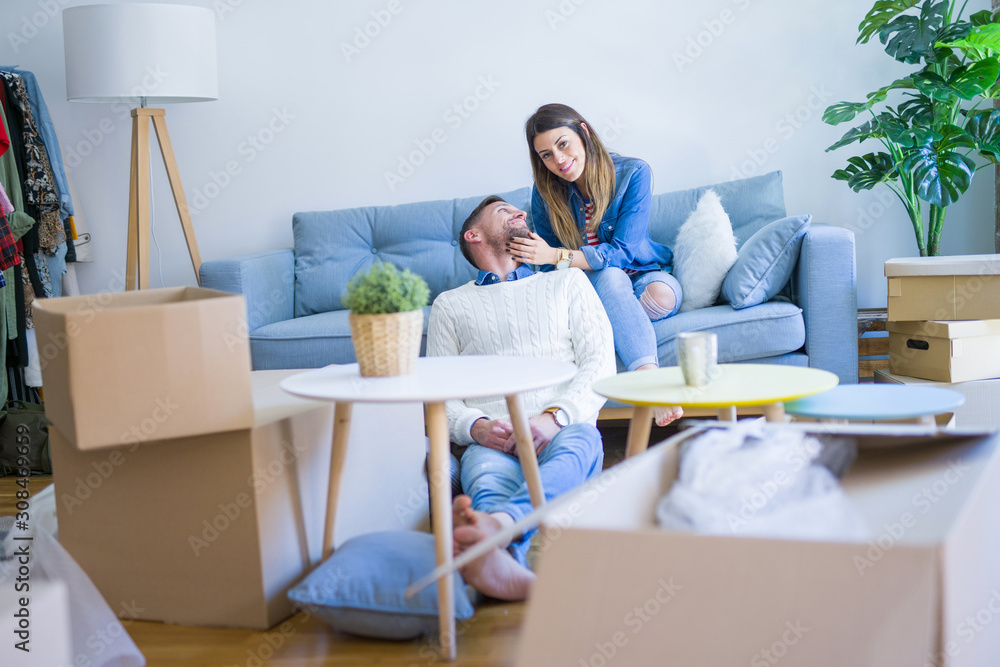 Young beautiful couple sitting on the sofa drinking cup of coffee at new home around cardboard boxes Young beautiful couple sitting on the sofa drinking cup of coffee at new home around cardboard boxes