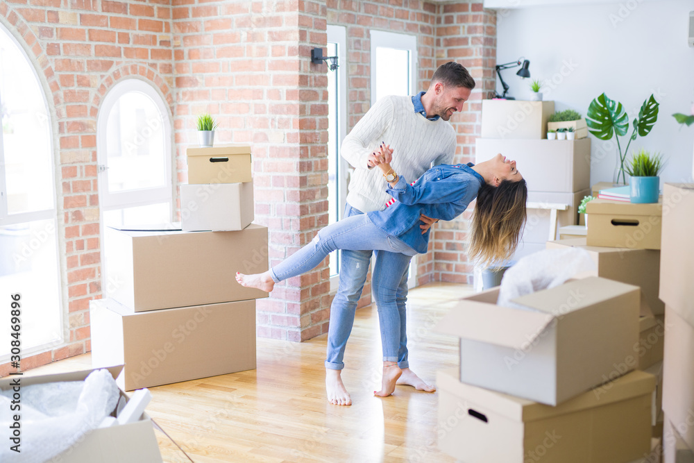 Young beautiful couple dancing at new home around cardboard boxes Young beautiful couple dancing at new home around cardboard boxes