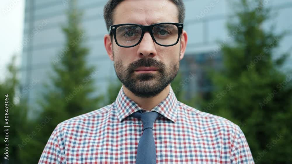 Portrait of handsome bearded guy in glasses wearing shirt and tie standing alone outdoors looking at camera. Professionals, business and management concept. Portrait of handsome bearded guy in glasses wearing shirt and tie standing alone outdoors looking at camera. Professionals, business and management concept.