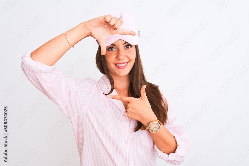 Young beautiful girl wearing pajama and sleep mask standing over isolated white background smiling making frame with hands and fingers with happy face. Creativity and photography concept. Young beautiful girl wearing pajama and sleep mask standing over isolated white background smiling making frame with hands and fingers with happy face. Creativity and photography concept.