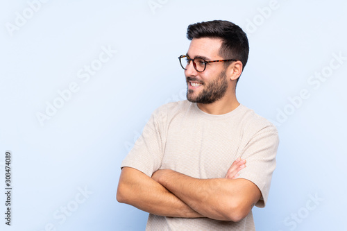 Young handsome man with beard over isolated blue background looking to the side