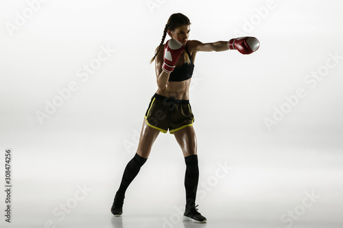 Fit caucasian woman in sportswear boxing isolated on white studio background. Novice female caucasian boxer training and practicing in motion and action. Sport, healthy lifestyle, movement concept. © master1305