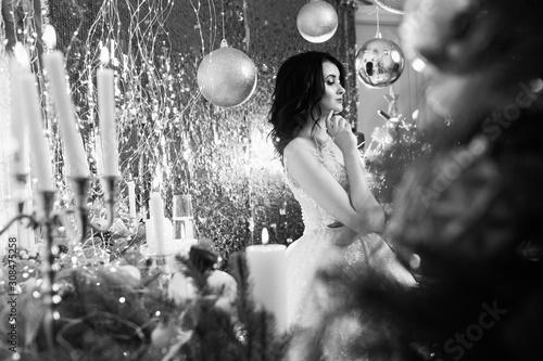 Black and white photo. Christmas, x-mas, winter, happiness concept - smiling woman. Happy young woman celebrating Christmas. Cute long-haired girls on the background of Christmas lights
