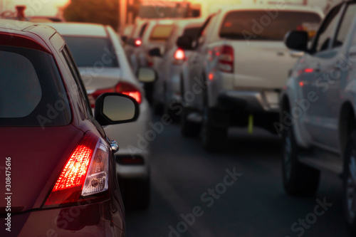Luxury of red car on the roads during rush hours for travel or business work. Open brake light. With blurred multiple cars parked during rush hours. © thongchainak