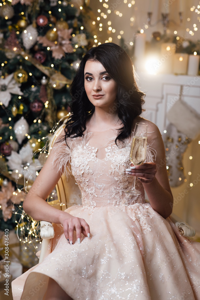 Sexy girl with glass of champagne at party, drinking champagne over holiday glowing background. Fashion and vogue. Beautiful girl in dress. Christmas Candles Sexy girl with glass of champagne at party, drinking champagne over holiday glowing background. Fashion and vogue. Beautiful girl in dress. Christmas Candles