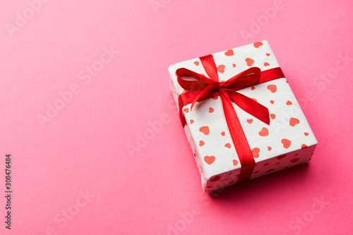 Gift box with red ribbon and heart on pink background, top view with copy space for text © sosiukin