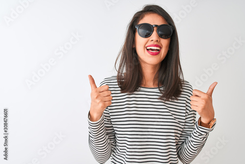 Chinese woman wearing striped t-shirt and sunglasses standing over isolated white background success sign doing positive gesture with hand, thumbs up smiling and happy. Cheerful expression and winner
