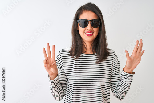 Chinese woman wearing striped t-shirt and sunglasses standing over isolated white background showing and pointing up with fingers number eight while smiling confident and happy.