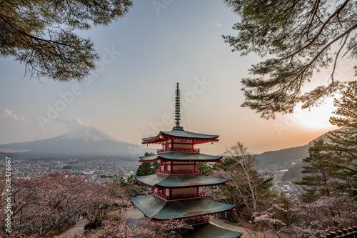 Sunset atmosphere at the Chureito Pagoda in front of the Mount Fuji with some cherry blossoms and framed by trees. Shimoyoshida, Japan
