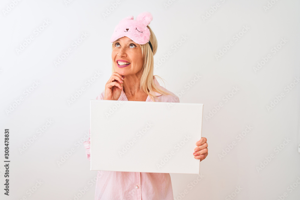 Middle age woman wearing sleep mask pajama holding banner over isolated white background serious face thinking about question, very confused idea Middle age woman wearing sleep mask pajama holding banner over isolated white background serious face thinking about question, very confused idea