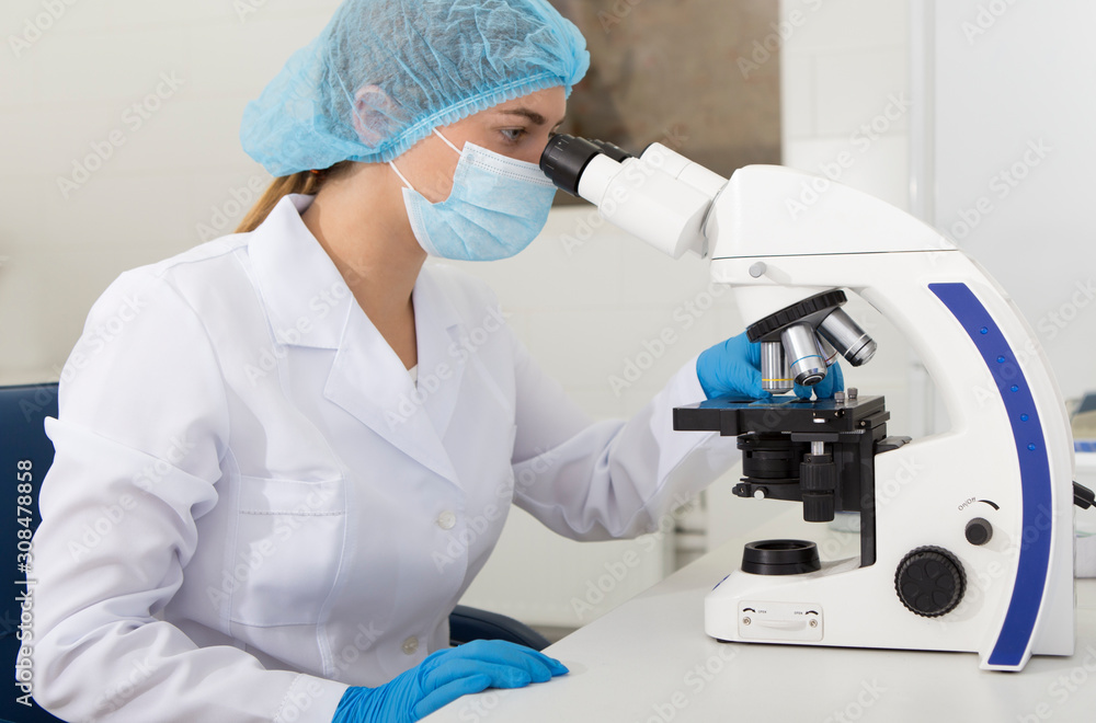 Young medical worker looking on samples through microscope Young medical worker looking on samples through microscope
