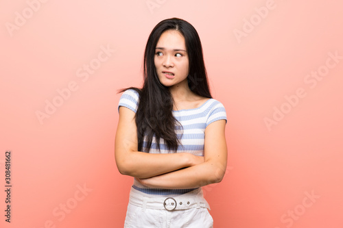 Teenager asian girl over isolated pink background with confuse face expression