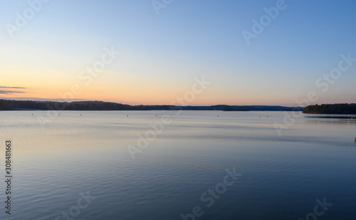Looking over Blewett Falls lake at sunset. The calm waters on the lake before the sunset. Blues on the lake and sky. A hint of warm orange on one side near the sun.