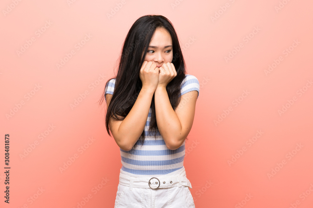 Teenager asian girl over isolated pink background nervous and scared putting hands to mouth Teenager asian girl over isolated pink background nervous and scared putting hands to mouth