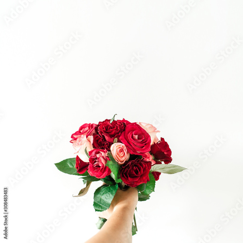 Female hand hold pink and red rose flowers bouquet isolated on white background. Holiday, Valentine's day present.