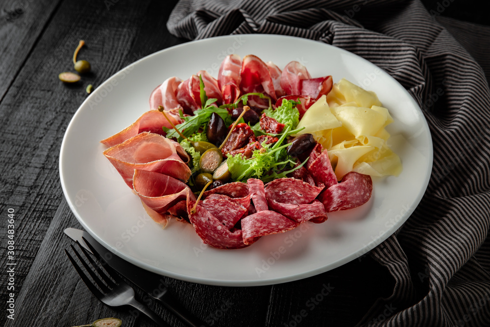 Appetizer of deli meats, salami, boiled pork, ginger, prosciutto, capers Restaurant menu. Background black boards. Appetizer of deli meats, salami, boiled pork, ginger, prosciutto, capers Restaurant menu. Background black boards.