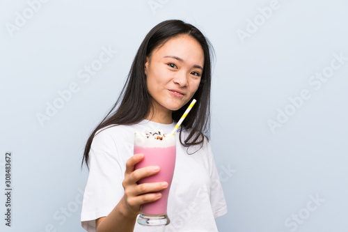 Teenager asian girl holding a strawberry milkshake with happy expression