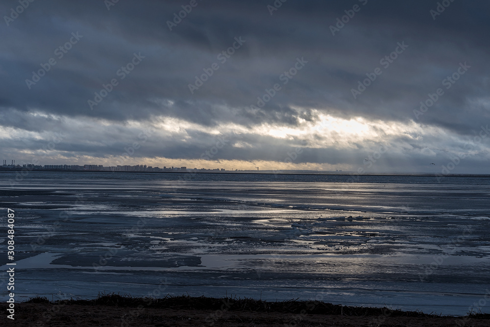 Obraz premium landscape on the outskirts of the city by the Bay with a dramatic sky and streams of light coming from the formed gap
