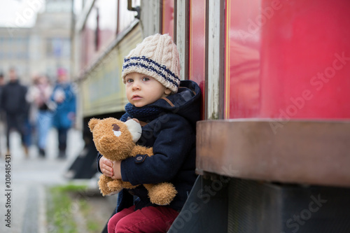 Fashion toddler boy with teddy bear toy in the city center