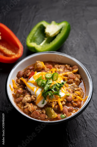 Texmex dish called "Chili con carne" with cheese and sour cream on dark background