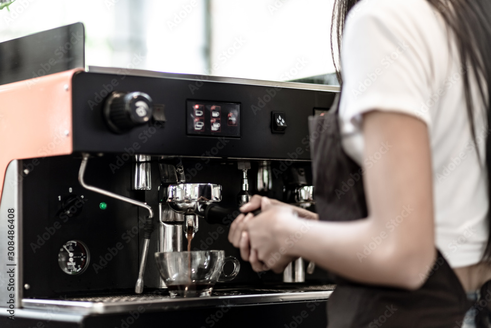 Hands of young woman barista was pressing the start button on the coffee machine, Coffee making cafe barista concept, Small business owner and work concept. Hands of young woman barista was pressing the start button on the coffee machine, Coffee making cafe barista concept, Small business owner and work concept.
