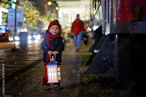 Sweet little toddler boy, holding lantern and a teddy bear at night in Prague