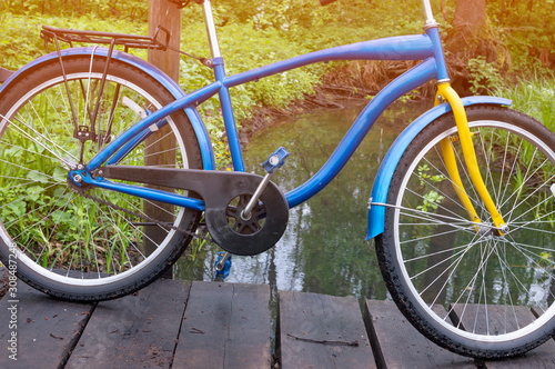bicycle on a wooden bridge over a small river on a background of forest