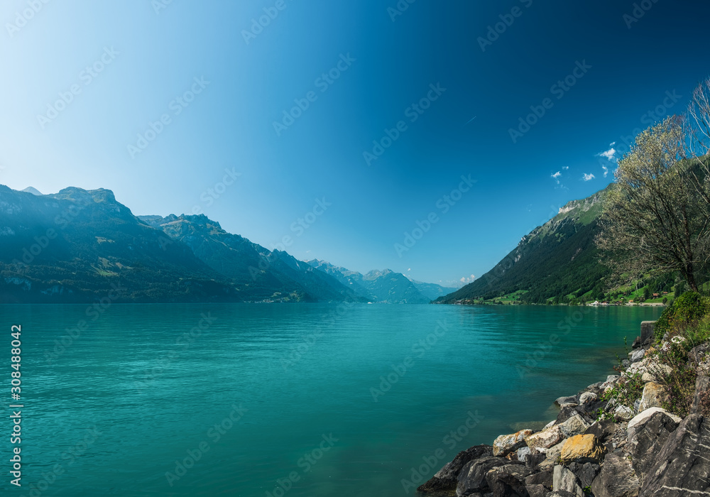 Idyllic sunny day on the Lake Brienz or Brienzersee in Berner Oberland, Canton of Bern, Switzerland. Scenic landscape with picturesque mountains, blue sky and turquoise water of lake