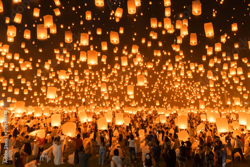 Thai people release sky floating lanterns or lamp to worship Buddha's relics at night. Traditional festival in Chiang mai, Thailand. Loy krathong and Yi Peng Lanna ceremony. Celebration background. © tampatra