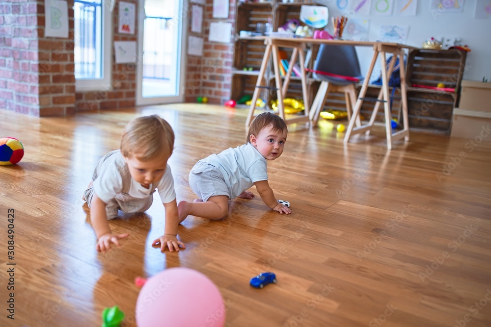 Fototapeta premium Beautiful toddlers playing around lots of toys at kindergarten