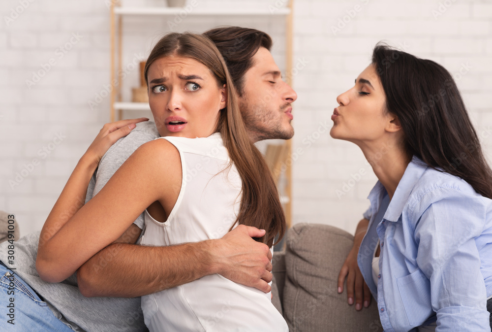 Girl Hugging Boyfriend While He Kisses Her Friend Sitting Indoor Girl Hugging Boyfriend While He Kisses Her Friend Sitting Indoor