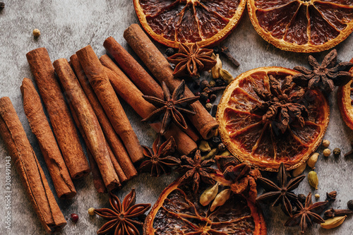 Christmas spice background. Cinnamon, dried oranges and anise on a grey background.