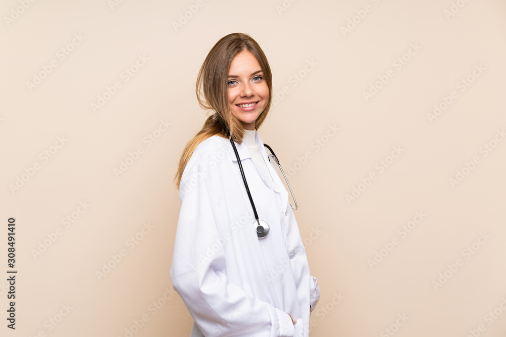 Young blonde woman over isolated background with doctor gown Young blonde woman over isolated background with doctor gown