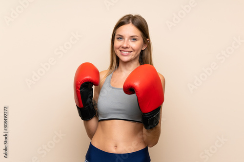 Young blonde girl with boxing gloves over isolated background © luismolinero