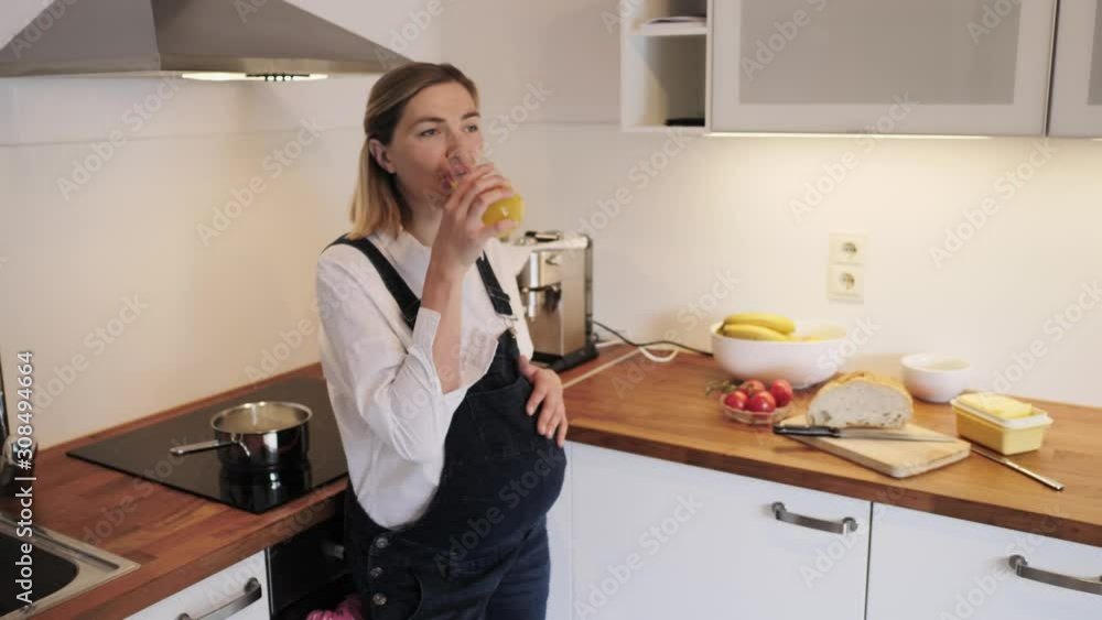 Pregnant girl drinks juice in the kitchen. Pregnant girl drinks juice in the kitchen.