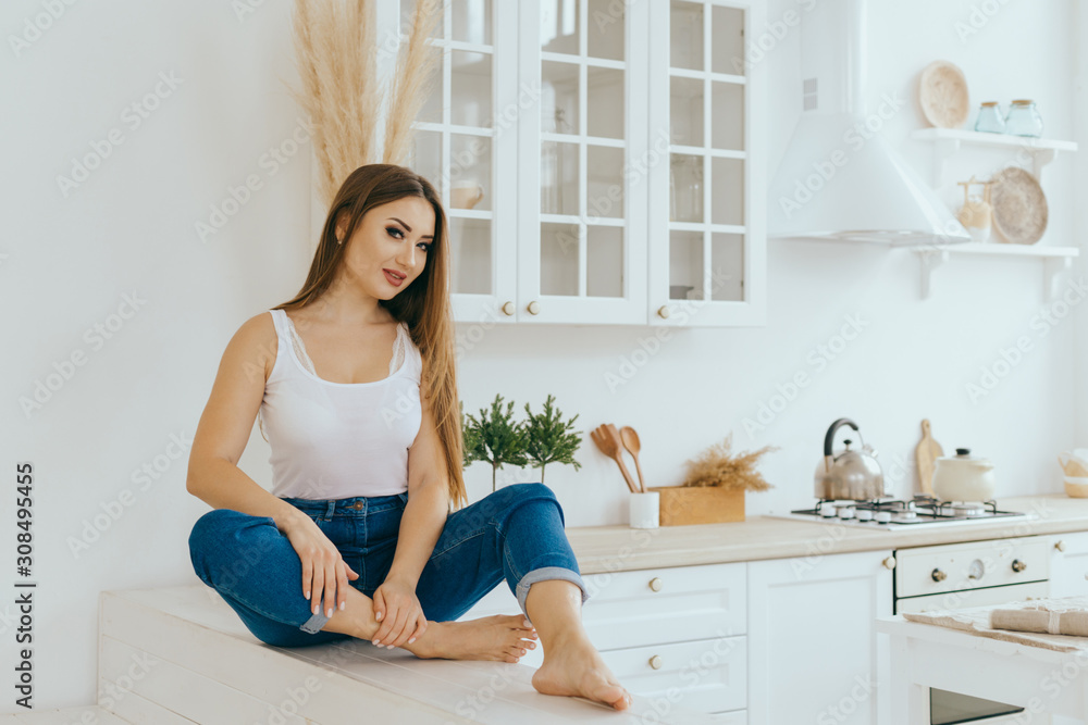 Portrait of a smiling young housewife in modern bright minimalistic Scandinavian kitchen Portrait of a smiling young housewife in modern bright minimalistic Scandinavian kitchen