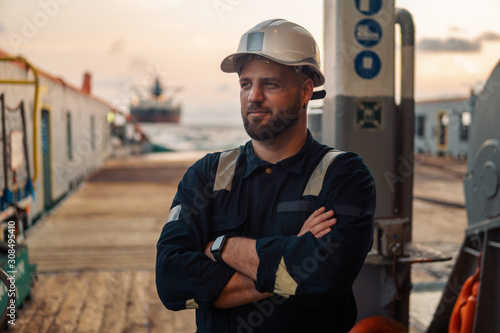 Marine Deck Officer or Chief mate on deck of offshore vessel or ship , wearing PPE personal protective equipment - helmet, coverall photo
