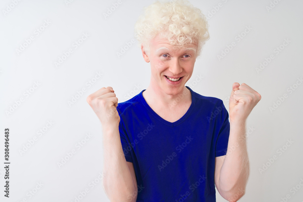 Young albino blond man wearing blue casual t-shirt standing over isolated white background celebrating surprised and amazed for success with arms raised and open eyes. Winner concept. Young albino blond man wearing blue casual t-shirt standing over isolated white background celebrating surprised and amazed for success with arms raised and open eyes. Winner concept.