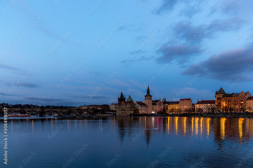 Obraz premium The center of Prague Czech Republic and its biggest landmark on the Vltava river Charles Bridge and the beautiful waterfront illuminated during Christmas at sunset with reflections