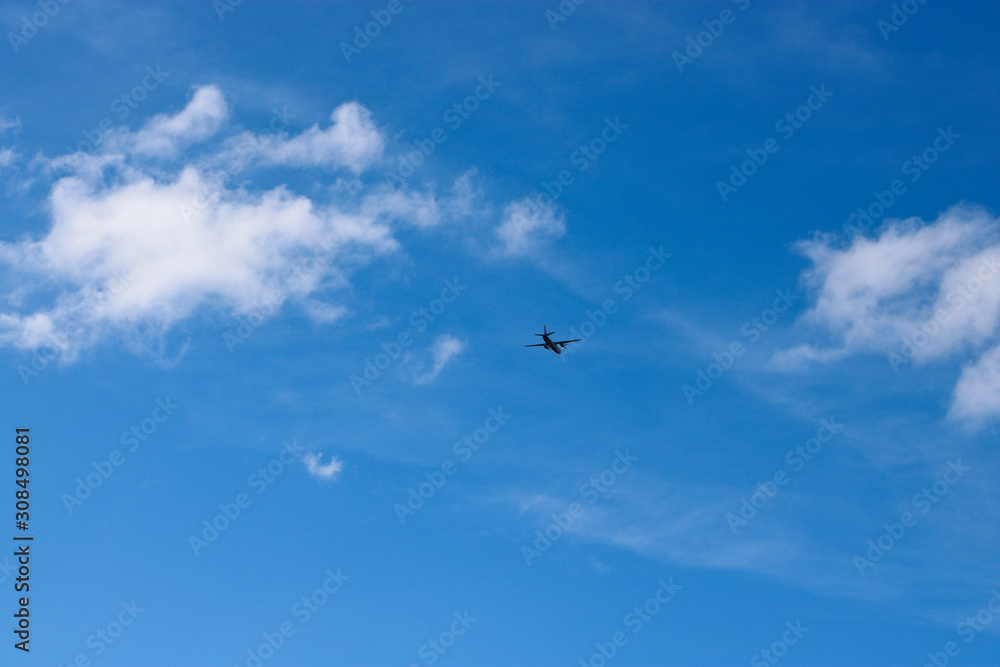 A plane flying against a blue sky with cirrus and cumulus clouds. The concept of travel, vacation, adventure.