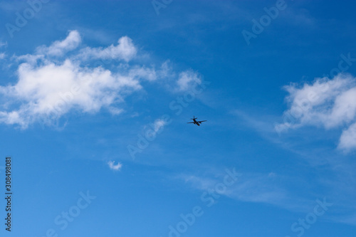 A plane flying against a blue sky with cirrus and cumulus clouds. The concept of travel  vacation  adventure.