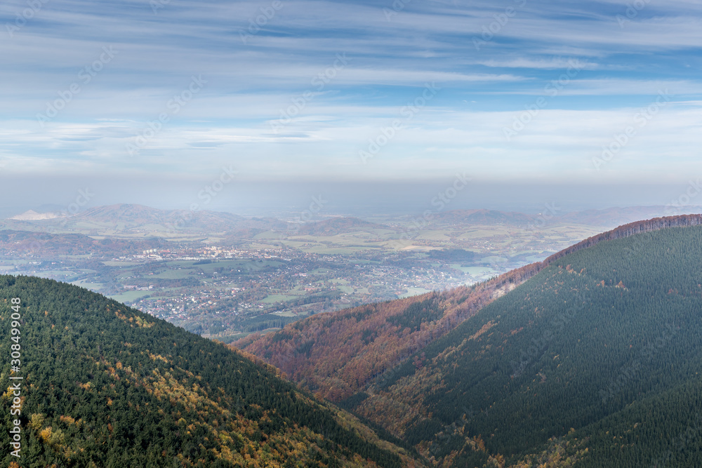 Obraz premium Hills and mountains on the horizon of beautiful nature with city in the forest valley view into vast distance of the Beskids Area during a windy sunny day captured in Radhost Pustevny area