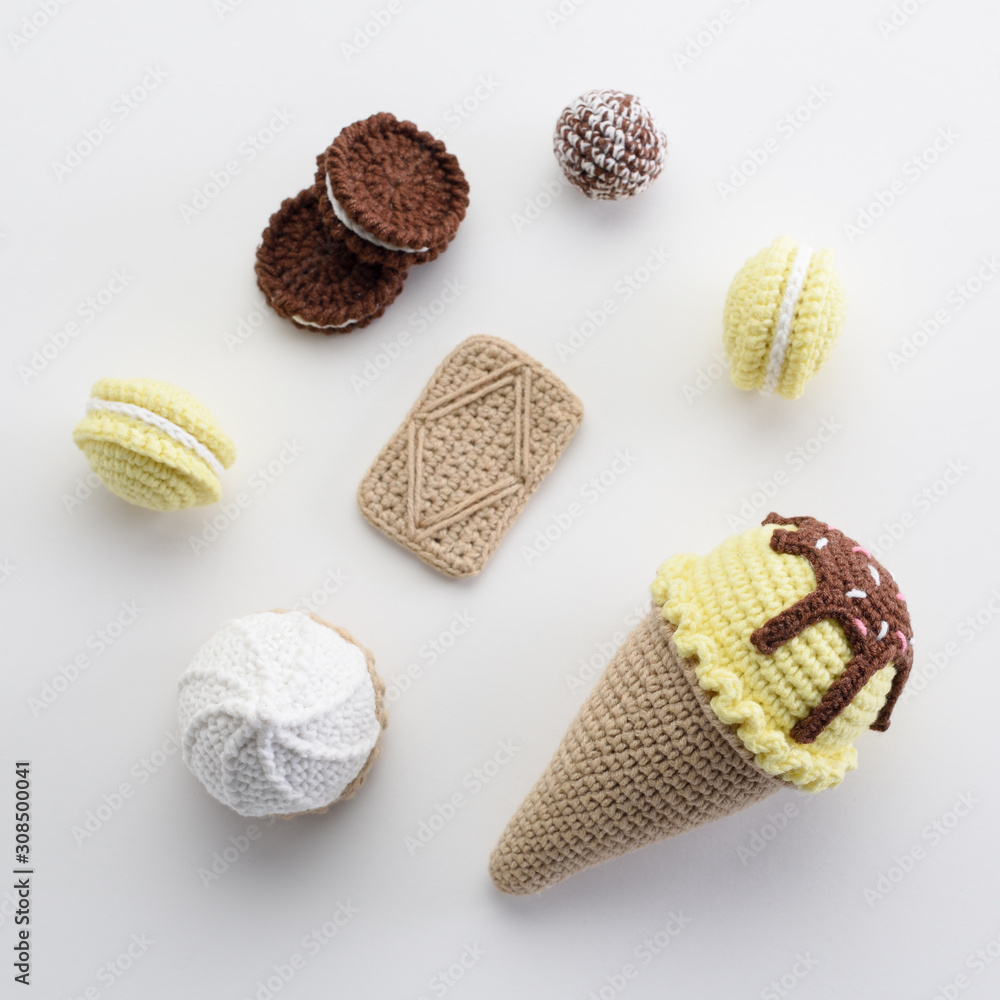 Cute homemade amigurumi toys flat lay. Knitted lemon and chocolate ice cream, macarons and cookies on white background Cute homemade amigurumi toys flat lay. Knitted lemon and chocolate ice cream, macarons and cookies on white background