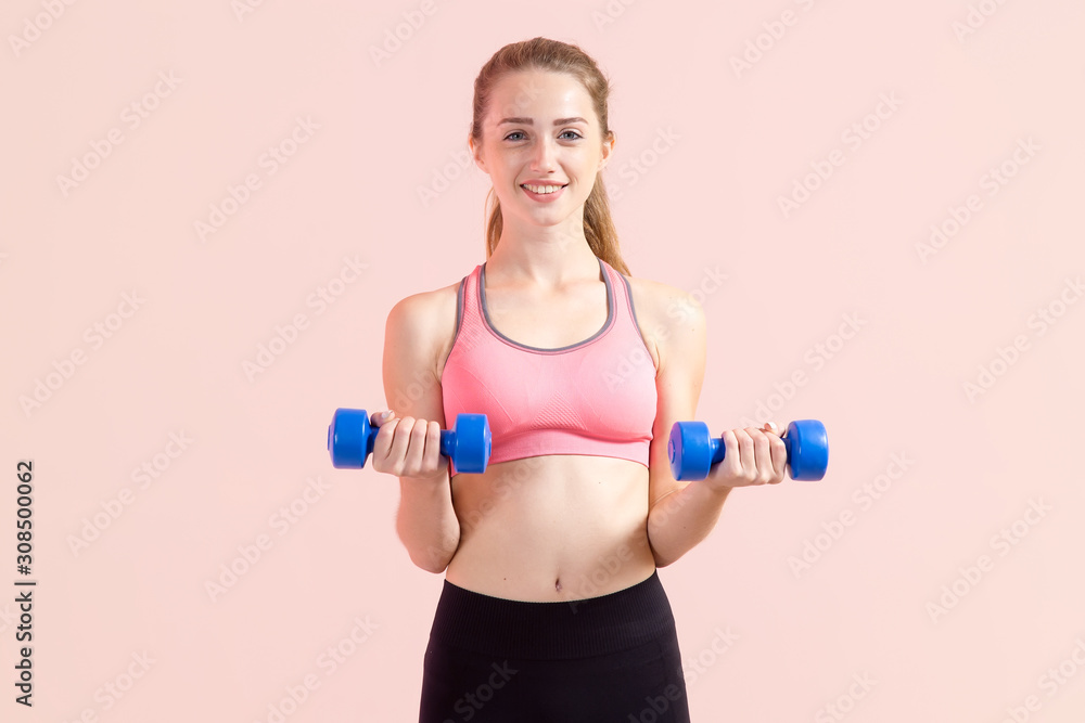 Young woman with two dumbbells in hands, standing on a pink background. Fitness exercise. Young woman with two dumbbells in hands, standing on a pink background. Fitness exercise.