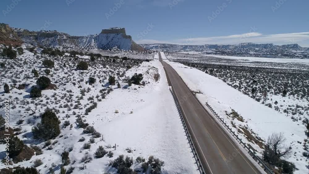 Flying along road through the vast snowy landscape in Utah as car drives past on HWY 12 in winter.