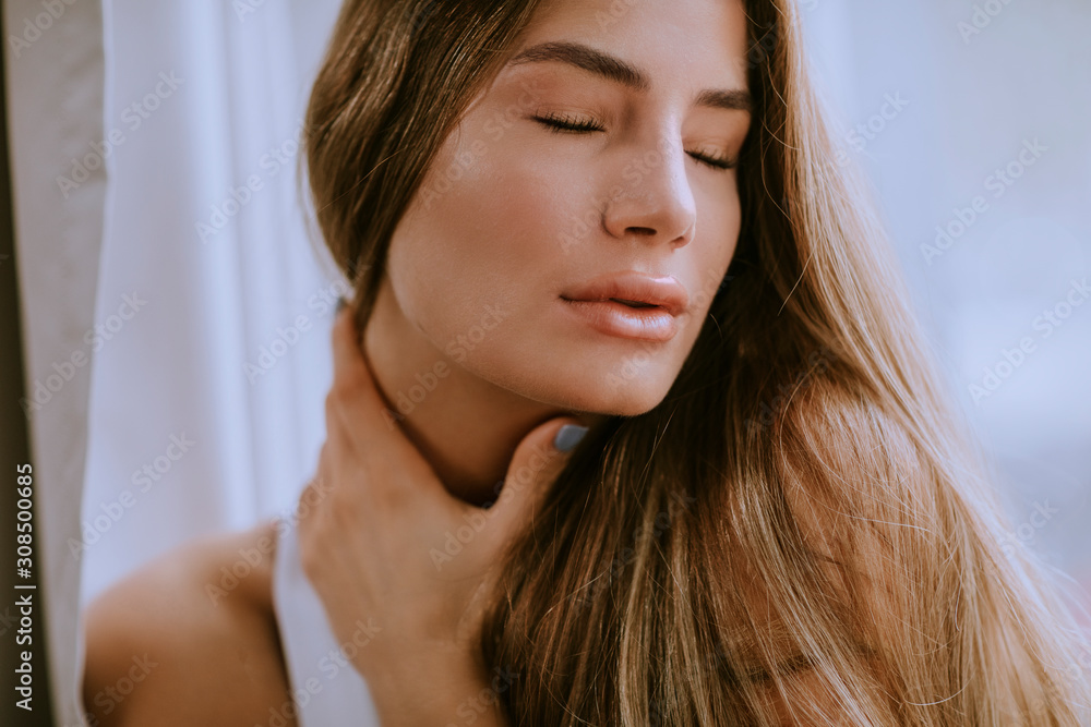 Young long hair  female brunette in front of the window