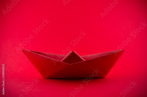 Paper boat isolated on red background © fabianodp