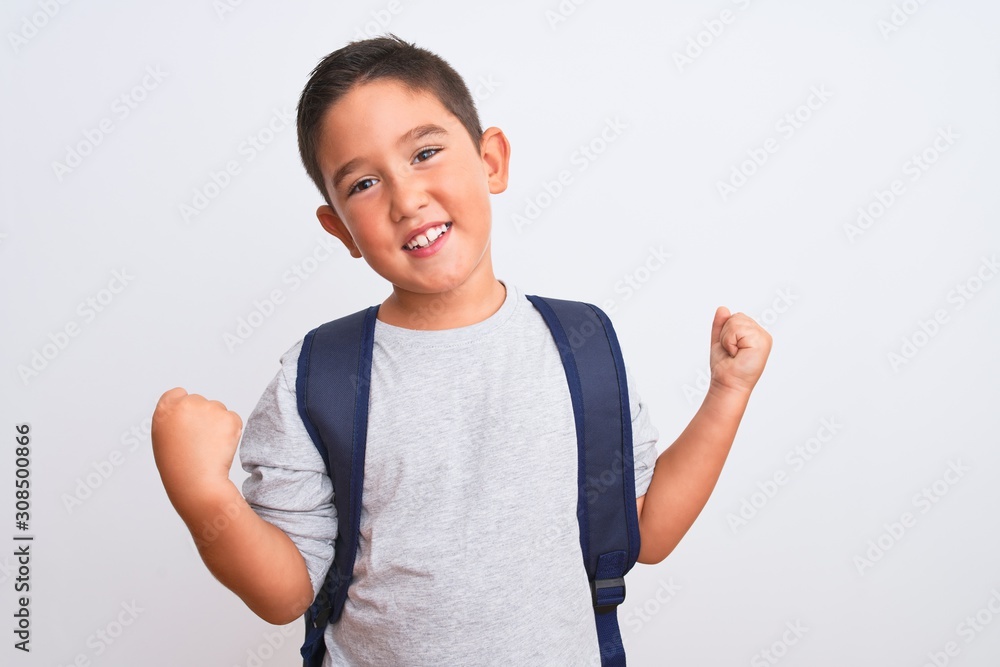 Beautiful student kid boy wearing backpack standing over isolated white background very happy and excited doing winner gesture with arms raised, smiling and screaming for success. Celebration concept. Beautiful student kid boy wearing backpack standing over isolated white background very happy and excited doing winner gesture with arms raised, smiling and screaming for success. Celebration concept.