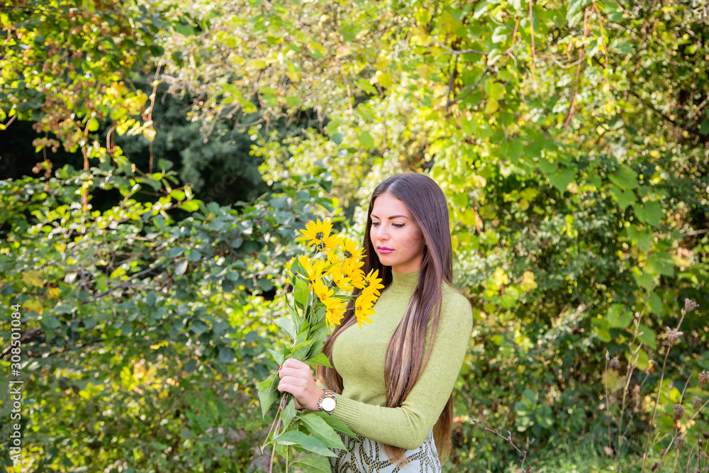 Outdoors portrait of beautiful young brunette woman with long hair and flowers in the park Outdoors portrait of beautiful young brunette woman with long hair and flowers in the park